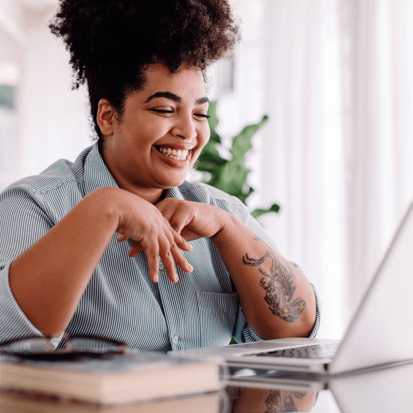 Pessoa com cabelo crespo, usando camisa listrada, digitando em laptop, com plantas ao fundo. Docusign em uso.