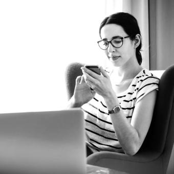 Woman sitting in hotel room with smartphone