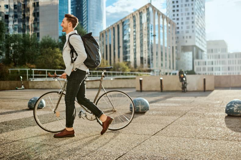 Homem andando ao lado da bicicleta na cidade