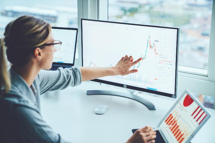 Uma mulher analiza gráficos financeiros na tela de seu computador