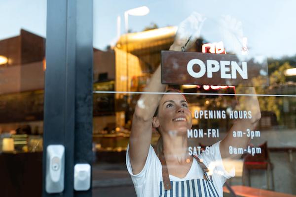 woman putting open sign in store window