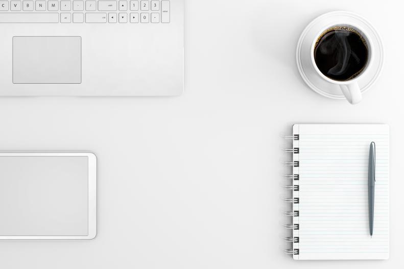 Schreibtisch mit Komputer, Kaffe und Notizbuch