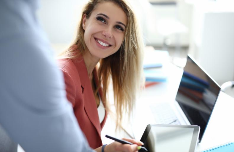 Una mujer sonríe mientras firma un documento en la pantalla de una tableta