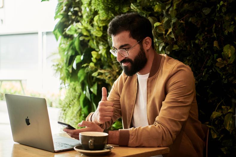 Man on laptop with coffee signing agreement
