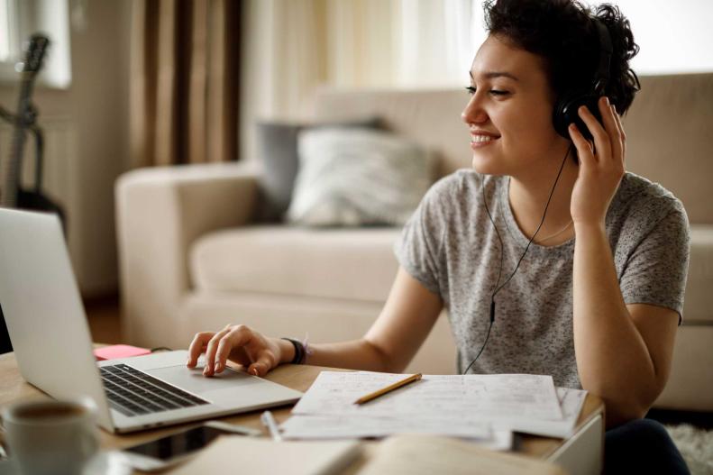Una joven trabaja en su computadora mientras escucha musica en sus auriculares