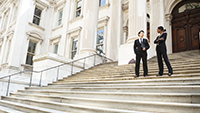 Two people in suits standing on the steps of a government building.