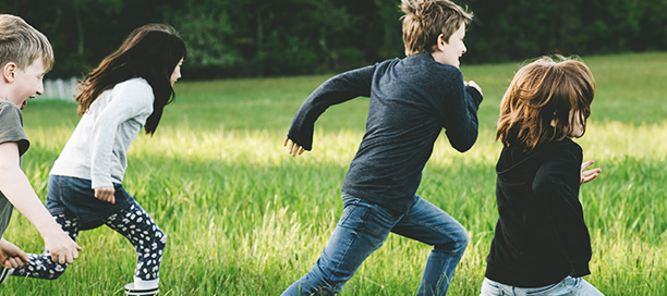 Children running through grassy field