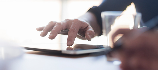 Man using digital tablet on desk, close up of hand