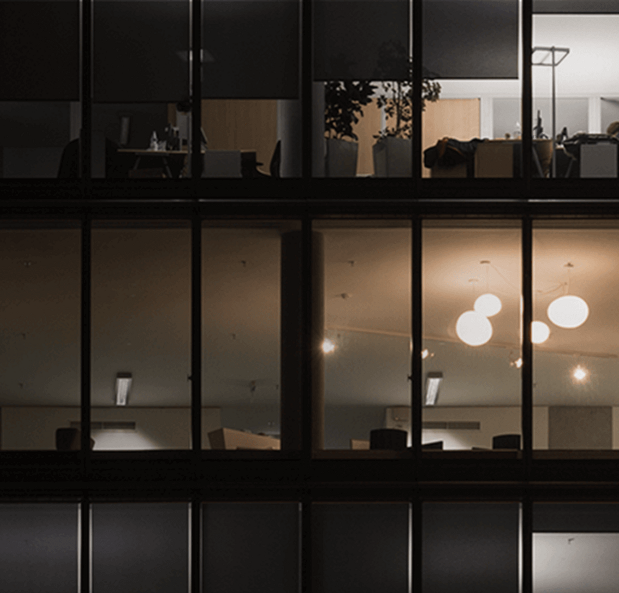 An image of three mostly dark floors in a multi-story office building at night.