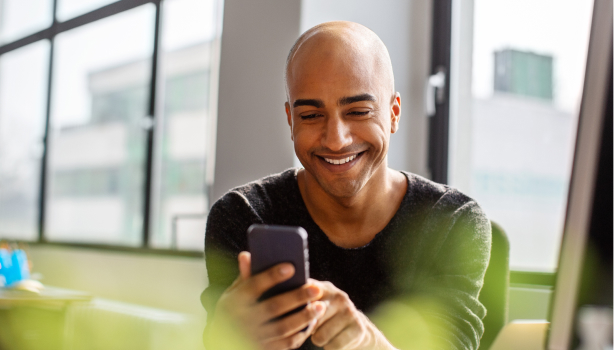 A man smiling as he views his mobile phone