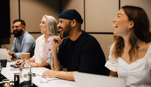 Colegas sorrindo em uma sala de conferência, fazendo uma reunião no escritório