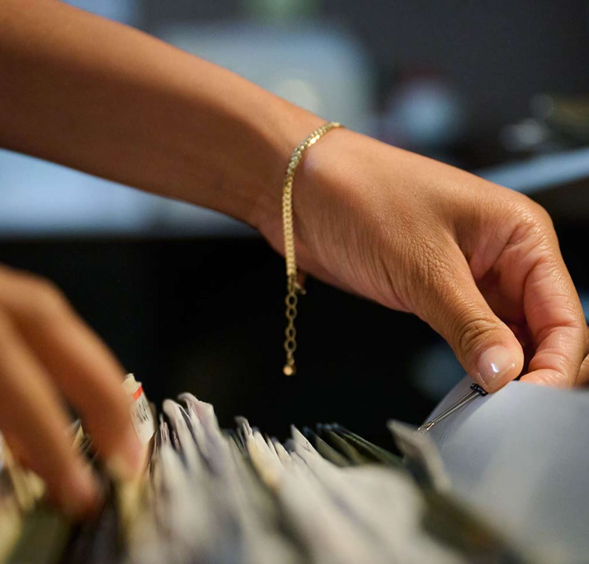 Mãos vasculhando arquivos e uma pessoa segurando um tablet digital no qual está visualizando o painel Docusign CLM