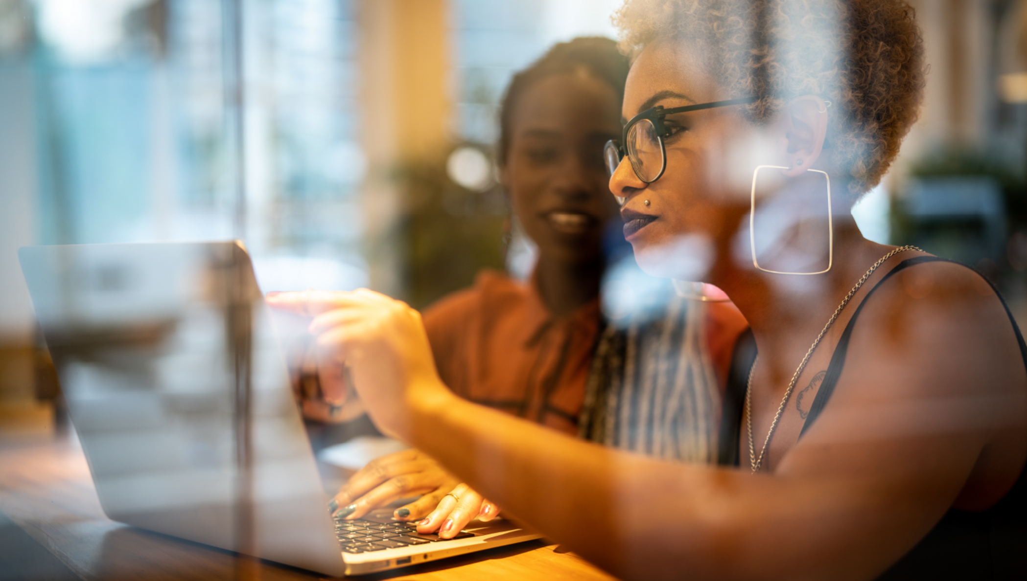 Duas mulheres conversando, apontando para a tela de um computador