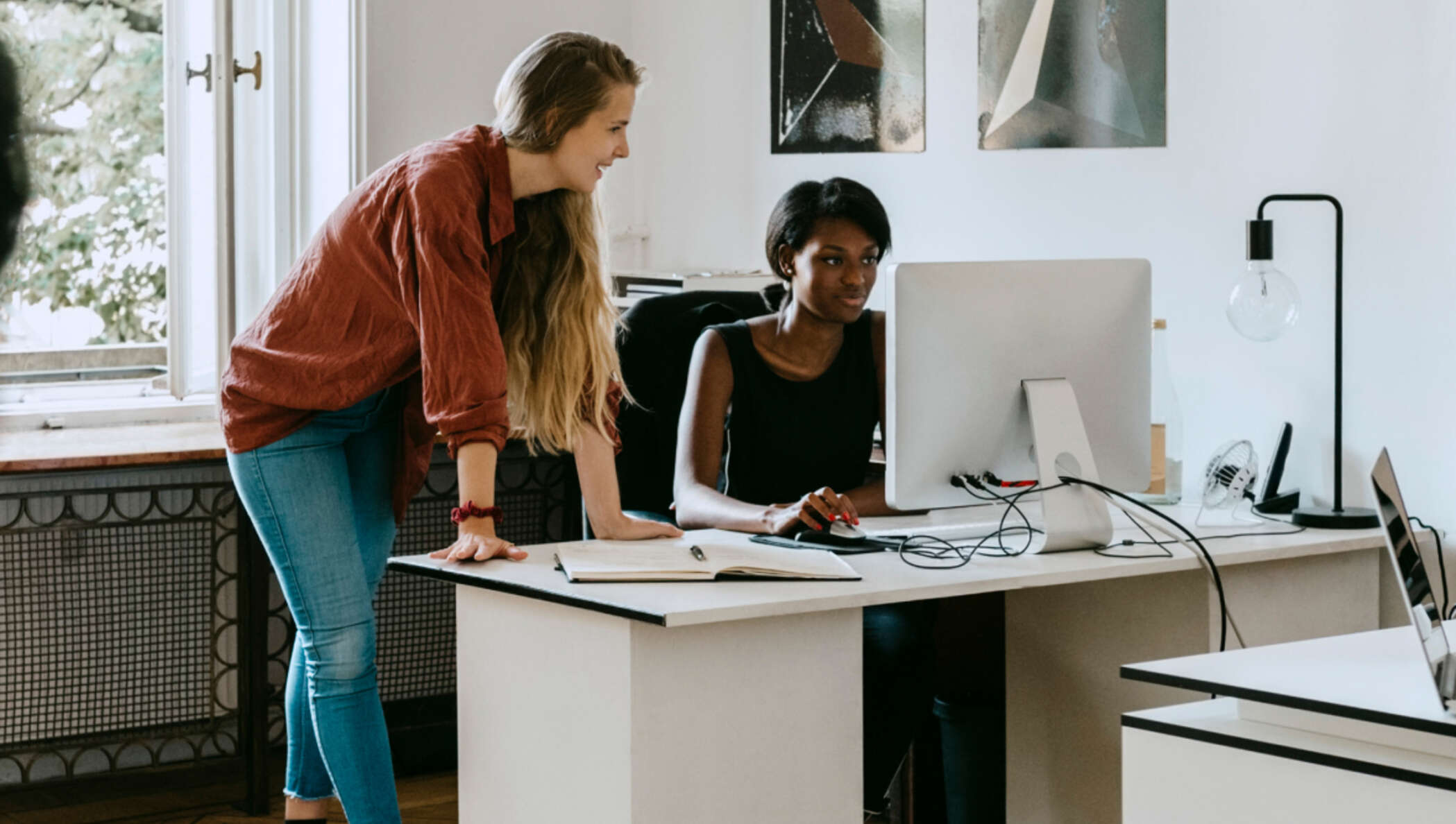 Colegas discutindo em uma mesa e olhando para o monitor de um computador no escritório