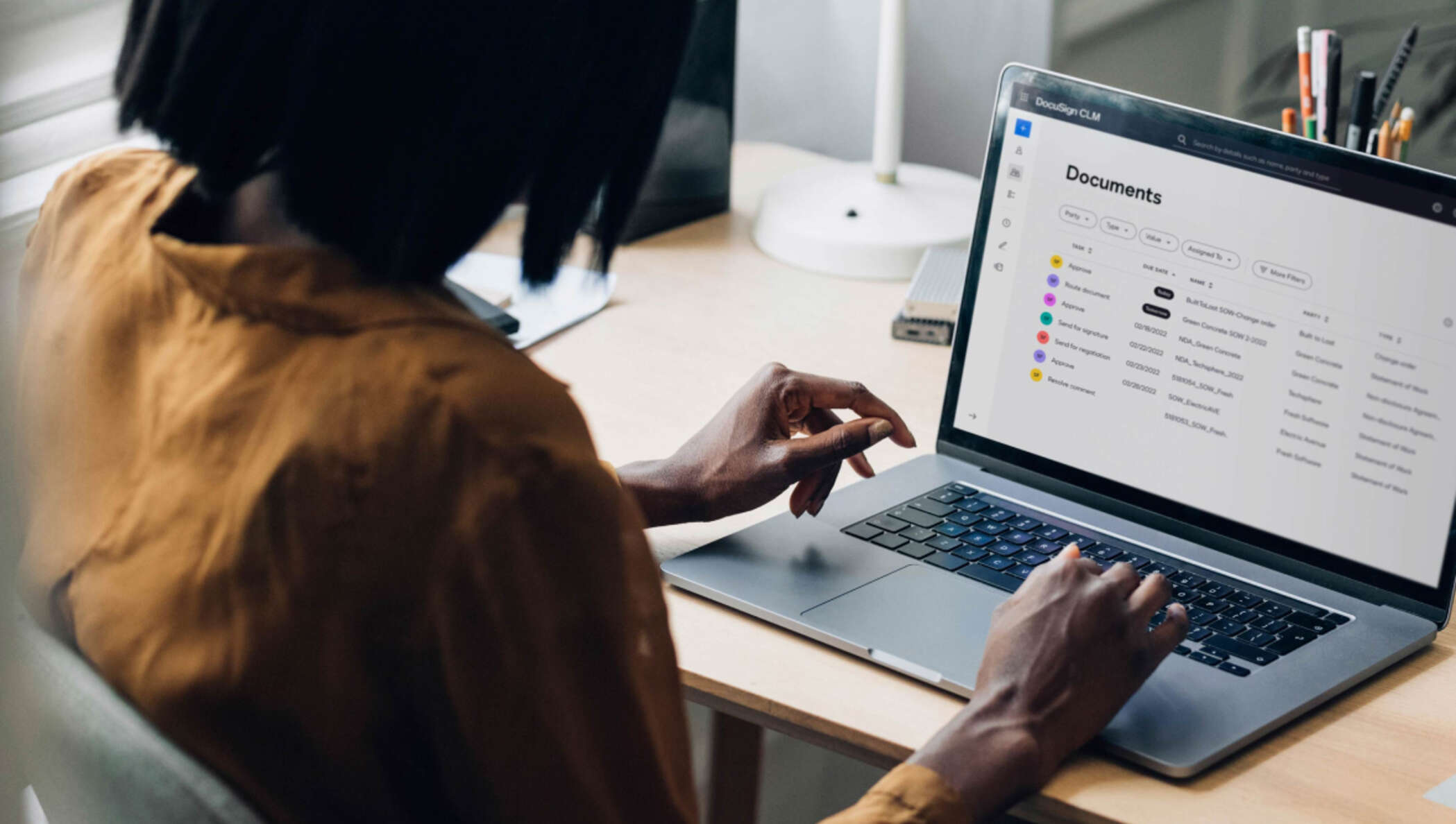 Uma profissional visualizando o painel do Docusign CLM no computador.