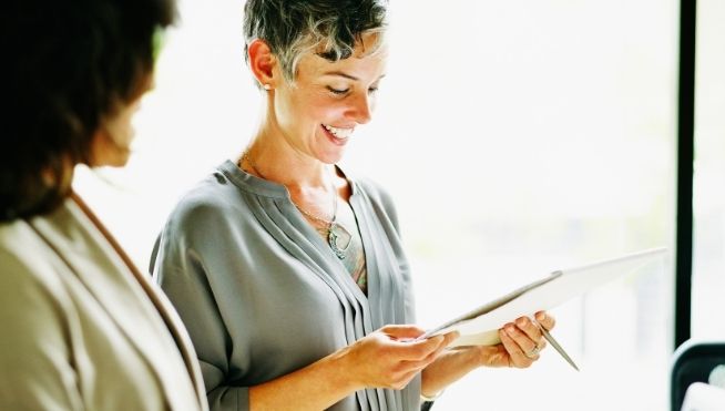 Smiling business woman looks at notepad